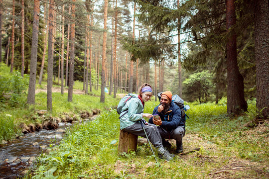 Father and daughter hiking in the forest using smartphone GPS