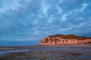 Stunning view of rugged coastline at sunset, with dramatic clouds and tranquil beach setting the scene beautifully