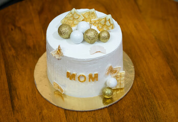 decorated white cake for mother birthday kept at table at indoor from different angle