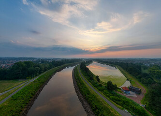 Scenic aerial view of a peaceful waterway landscape during dusk with beautiful sky and lush greenery.