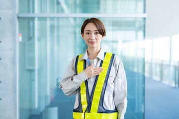 胸に手を当てる作業着を着た女性