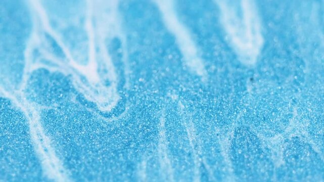 Glitter overlay. Colored fluid. Abstract blue shimmering art wave white whirling lines motion sand grain texture depth sharpness background blur.