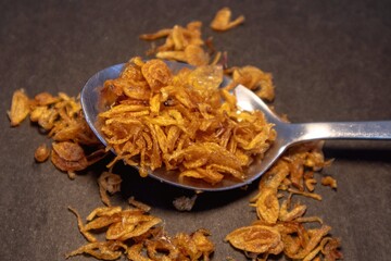 Fototapeta premium Crispy fried onions or roasted onion on the spoon on dark background