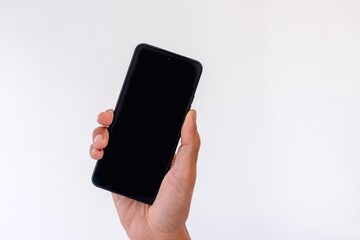 A man's hand holding a smartphone with blank screen in vertical orientation. Copy space.