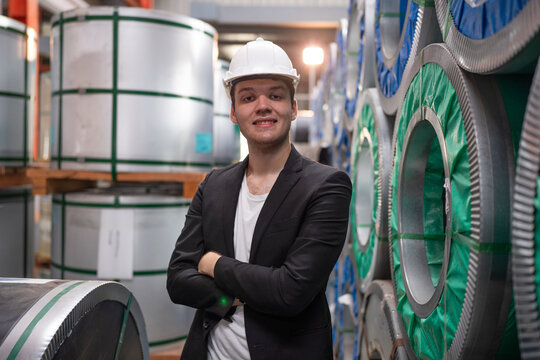 Portrait of male Manager or Chief Engineer Wearing Hard Hat Monitoring Production Conveyor in modern industrial factory.