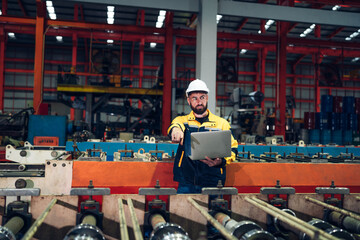 Industrial man engineer wear uniform and helmet using laptop are checking system machine at factory. Workers industrial factory. Machine maintenance technician operation concept.