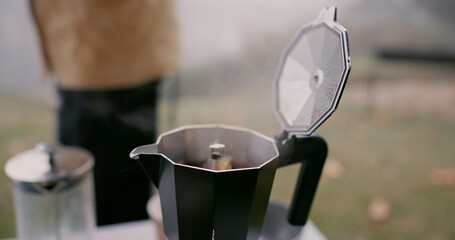 Moka pot, espresso and cup outdoor in winter storm by person for hiking, travel and cozy relax with peace. Hot beverage, coffee and calm in nature for adventure and drink as latte from french press