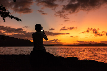 Silhouette of a boy sitting on the beach at sunset