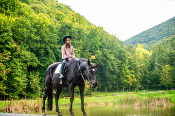 Little girl riding a horse at summer. Child girl rides horse on the outdoors in the middle of the...
