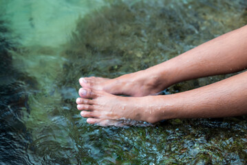 A girl is soaking her feet in sea water