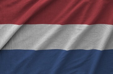 Netherlands flag depicted on folded wavy fabric of old cloth close up