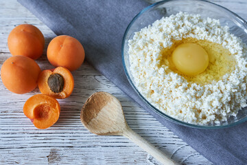 Bowl with cottage cheese, eggs and apricots on wooden background