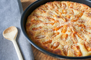 Homemade apricot pie in a baking dish on a wooden table
