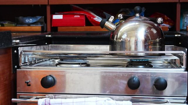 Kettle on gimballed gas stove in sailing yacht during yachting