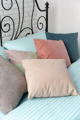 White Brick Wall Bedroom With Blue And Beige Pillows On A Bed With Black Metal Headboard