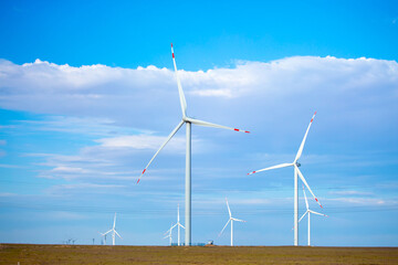 Fleet of power generators in motion. The blades of the wind farm rotate against the sky. The...
