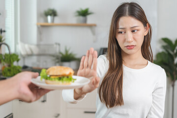 Diet, struggle asian young woman hand gesture reject to eat burger, push out or deny fast, junk...