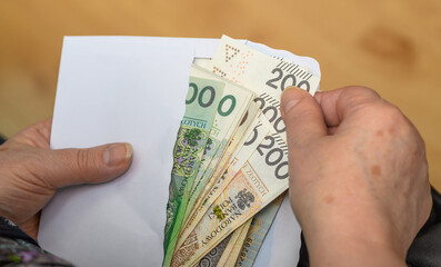 Seniorka wyciąga polskie pieniądze z koperty