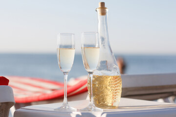 A bottle of wine, two glasses, and a beach
