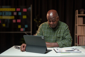 African American businessman upset about business failure Headache or feeling stressed, tired, sleepy with work problems while sitting at an office table with information and news on a laptop.