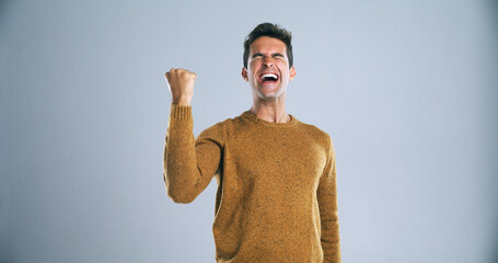Man, fist and happy for celebration in studio with shout, success and goals for bonus by background. Person, excited and winning for profit, prize and giveaway with lottery, contest or competition