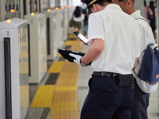 夏の名古屋駅のホームで仕事する男性駅係員の姿