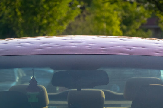 Calgary, Alberta, Canada. Jul 12, 2024. A close up to a car with hail damage and windshield that is cracked with the hood dented.