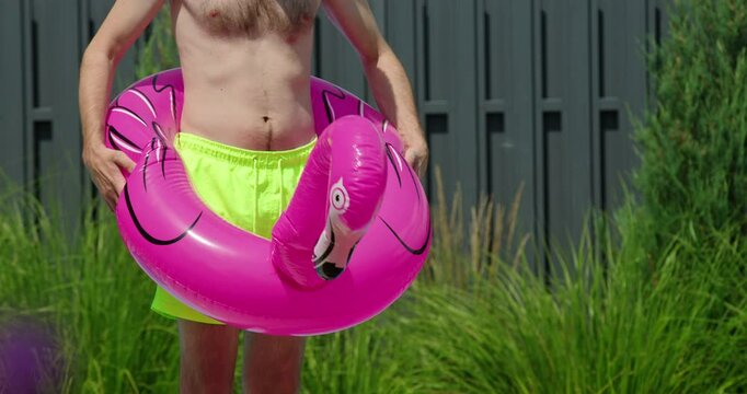 A man dancing in a flamingo-shaped inflatable ring, enjoying a fun moment.