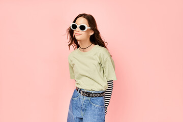 Fototapeta premium A stylish teenage girl confidently poses in a green shirt and sunglasses, exuding a vibrant and energetic aura.