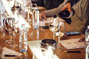 Person Pouring Glass of Wine at Table, Close-up