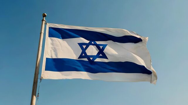 The Israeli flag flutters in the wind against a blue sky