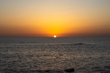 Fototapeta premium Sunrise photo of the sun rising over the horizon in the ocean.