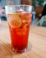 Fresh ice rose tea drink with slice of lime inside served in transparent glass. In isolated white background.
