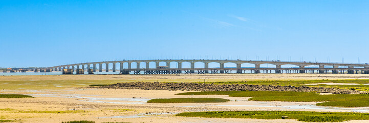 Obraz premium Bay of Chateau-d'Oleron and Ile d'Oleron bridge at low tide on a bright sun day Le Château-d'Oléron, France