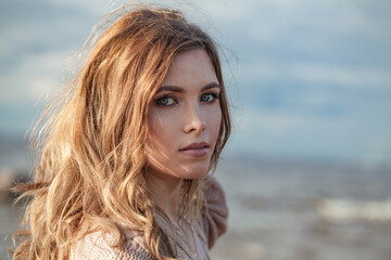 Glorious young adult female model with windy brown hair walking outdoor