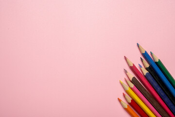 A row of colorful pencils on a pink background