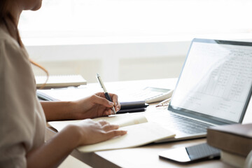 Young woman engages in online study at workspace.