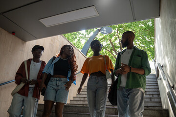 Stylish pleased group of african american students down to stairs to underpass chatting, gossips...