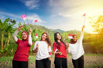 Portrait group of Indonesian women with excited expressions holding small Indonesian flag