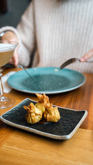 This close-up image captures a moment of fine dining as a diner uses a knife and fork to cut into an exquisitely presented gourmet dish. The food item, delicately wrapped and artistically plated on a 