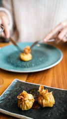 This close-up image captures a moment of fine dining as a diner uses a knife and fork to cut into an exquisitely presented gourmet dish. The food item, delicately wrapped and artistically plated on a 