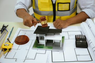 A judge with a gavel presides over a construction safety violation case. An architect and builder...