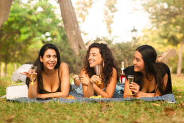 girlfriends laughing being happy at the park with a drink