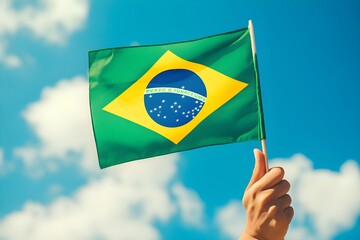 Hand holding Brazil national flag on blue sky. Happy Independence Day, Labor Day, Proclamation of the Republic. Background with copy space for greeting card, banner, poster