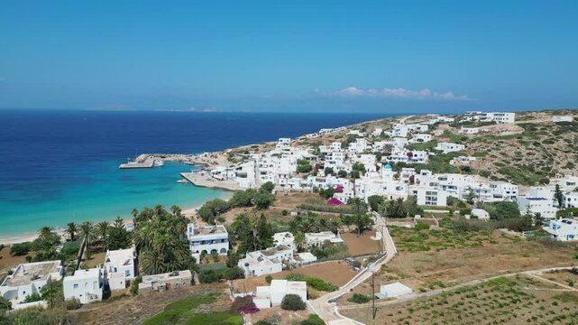 A scenic aerial view of Donousa, a small island in the Cyclades, showcasing its whitewashed buildings, turquoise waters, and lush vegetation.