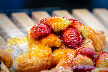 A pastry with strawberries on top. The pastry is yellow and has a lot of strawberries on it