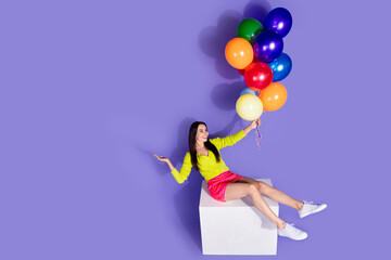 Photo of charming cheerful girl trendy clothes hold helium balloon look empty space isolated on purple color background