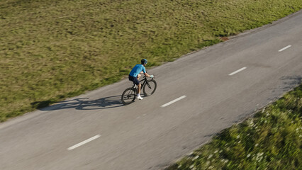Side view of a male professional racing bike rider cycling on a paved road on a summer sunny day,...