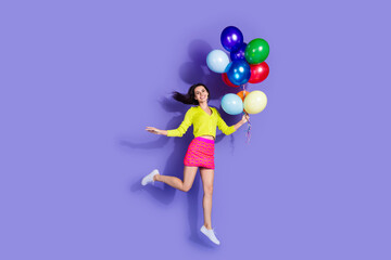 Fototapeta premium Photo of cheerful glad adorable lovely girl wear stylish clothes helium balloons isolated on purple color background