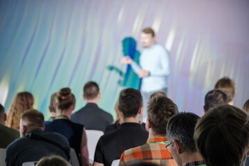 Obraz premium Group of people attending a business presentation, focusing on the speaker at the front of the room. Professional setting for corporate or educational event.